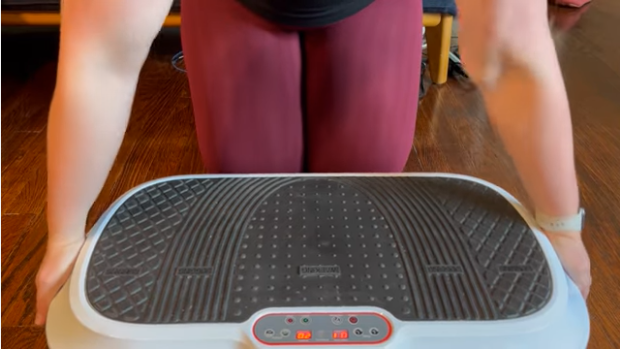A woman with her hands on a vibration plate to help manage her arm lipedema symptoms.